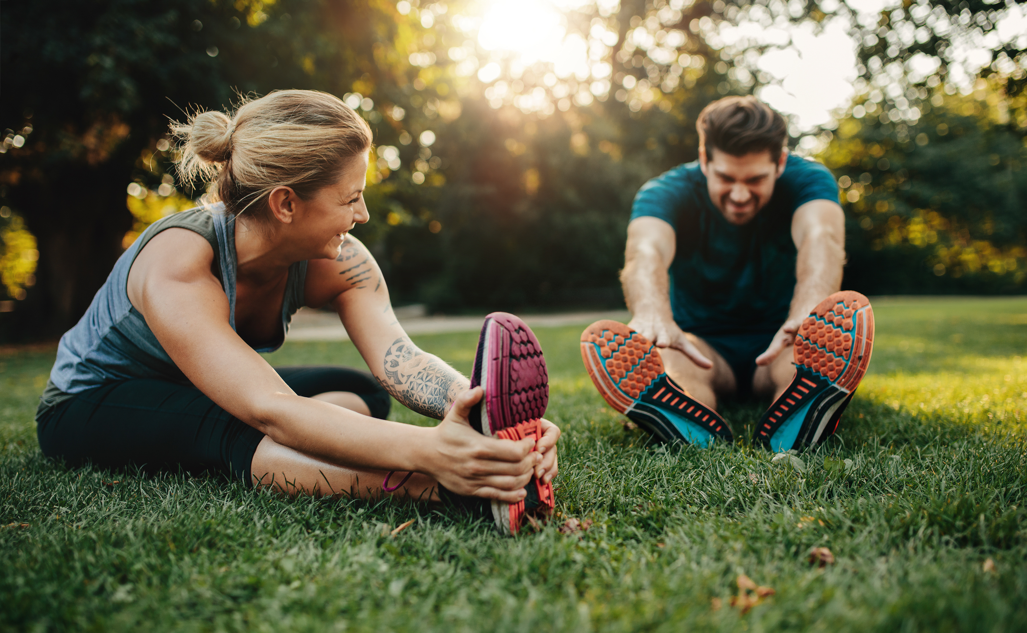 Young caucasian couple exercising in park Happy young man and woman stretching in the park. Smiling caucasian couple exercising in morning.